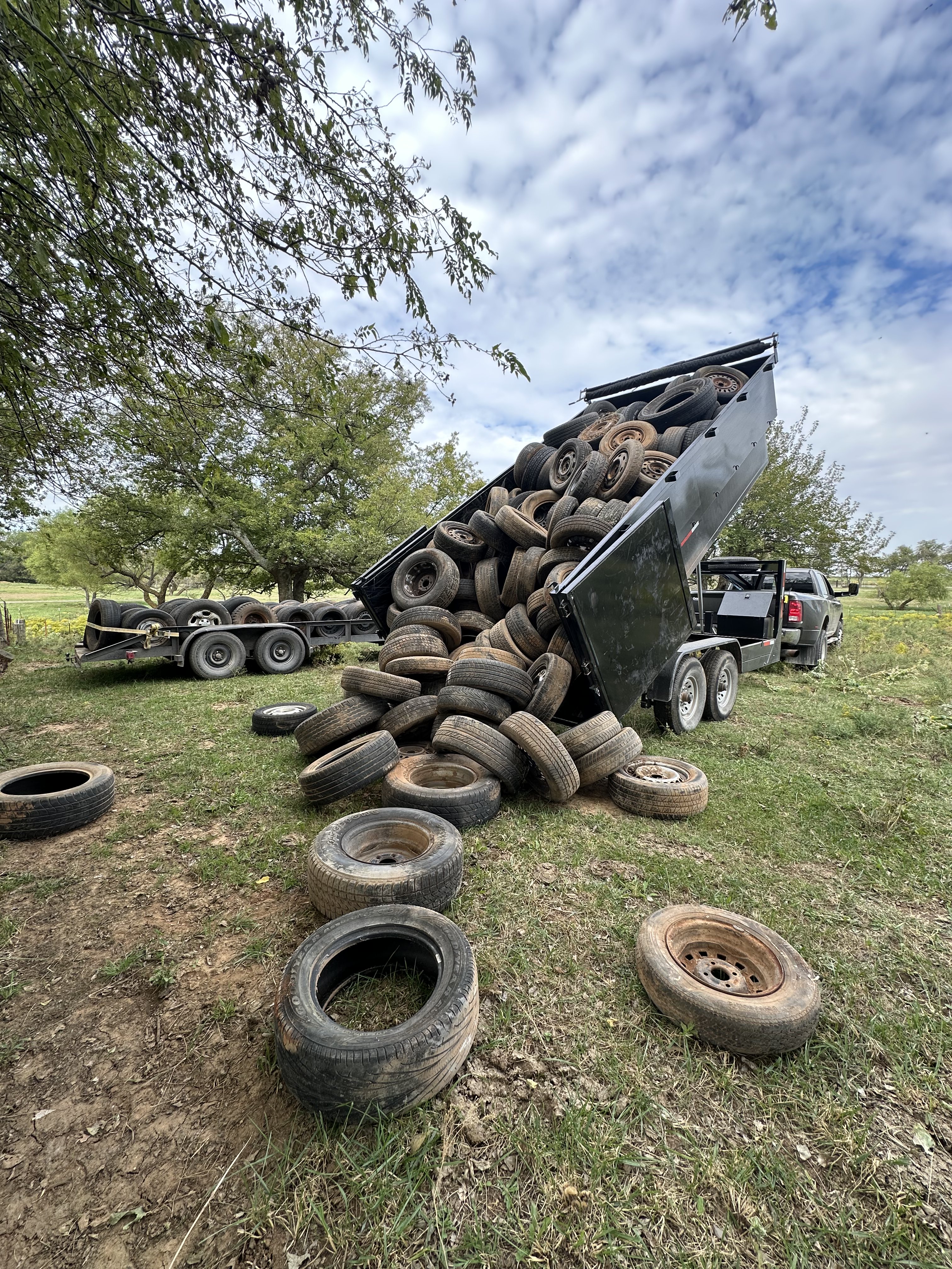 Big Project Solutions dump trailer unloading tires during junk removal in Oklahoma City rural area